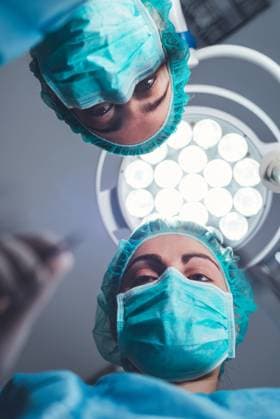 From below female surgeons in medical uniform using professional tools while standing under bright light in operating theater, Model released Copyright: xDavidxHerraezx MR