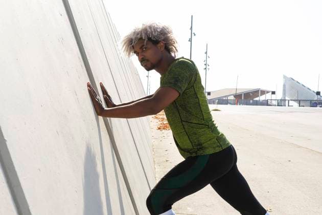 IMAGO Creative: Sport in der Stadt Black sportsman stretching during fitness workout near modern building on city street looking at camera Copyright: xDavidxMunozx Model Released