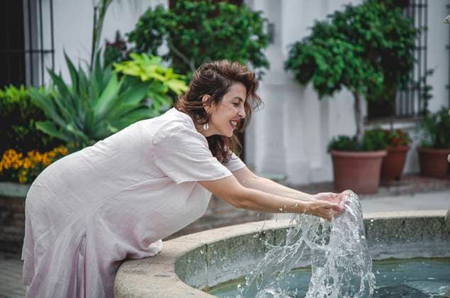 IMAGO Creative, Jahreszeit Sommer, Sommer in der Stadt Side view of happy cheerful playful woman bending over fountain and drawing water in hands in Marbella street Copyright: xEduardoxLopezx Model Released