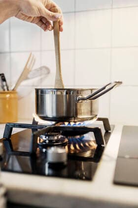 IMAGO Creative: Clickbait, Rezepte und Kochen Cropped image of woman s hand holding spatula in sauce pan while cooking food on stove , model released Copyright: xMaskotx , MA44349