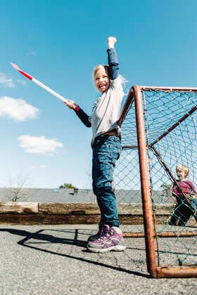 Low angle view of successful girl holding hockey stick against blue sky , model released, property released Copyright: xMaskotx , MA45198