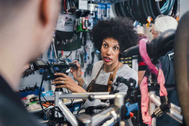 Female mechanic communicating with male customer in bicycle repair shop , model released, property released Copyright: xMaskotx , MA45293