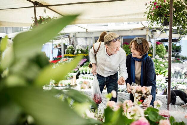 Happy senior couple talking while buying flowers at market , model released Copyright: xMaskotx , MA45749