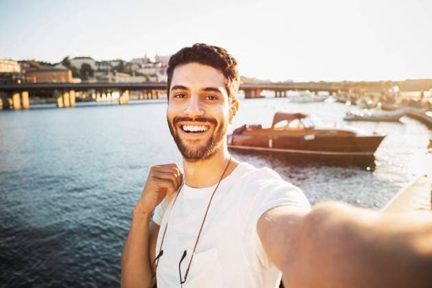 IMAGO Creative, Jahreszeit Sommer, Sommer in der Stadt Portrait of happy male tourist by river in city , model released Copyright: xMaskotx , MA47343