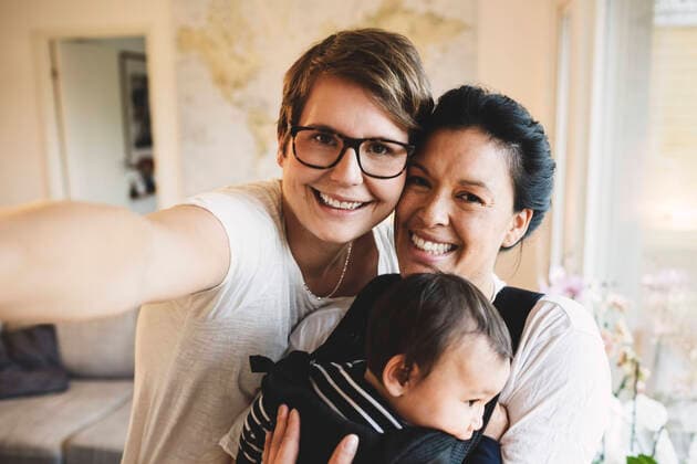 Portrait of smiling lesbian couple with baby girl standing at home , model released Copyright: xMaskotx , MA49054
