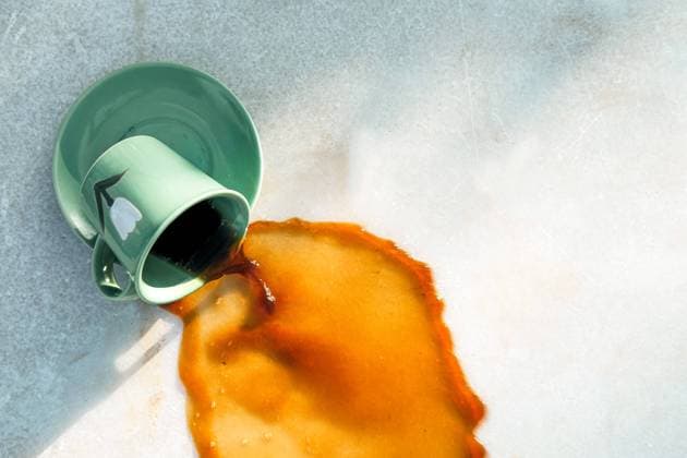 From above warm brown drink flowing from dropped green ceramic mug on saucer to gray table on cafe terrace Copyright: xFatimaxGuisadox Model Released