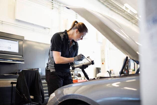 Female mechanic using technology while examining car at shop , model released, property released Copyright: xMaskotx , MA50468