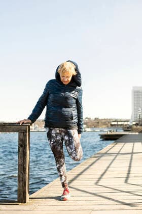 IMAGO Creative: Wintersport, Mode Senior woman stretching leg while standing on pier against clear sky , model released Copyright: xMaskotx , MA51042