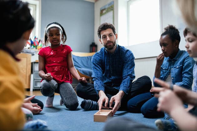 Teacher playing with children while sitting in classroom , model released, property released Copyright: xMaskotx , MA51254