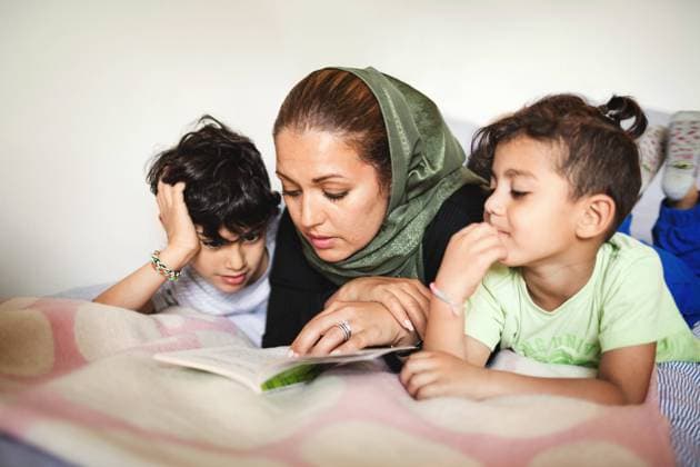 IMAGO Creative: Mutterschaft Mother reading book to boys while lying on bed at home , model released, property released Copyright: xMaskotx , MA51651