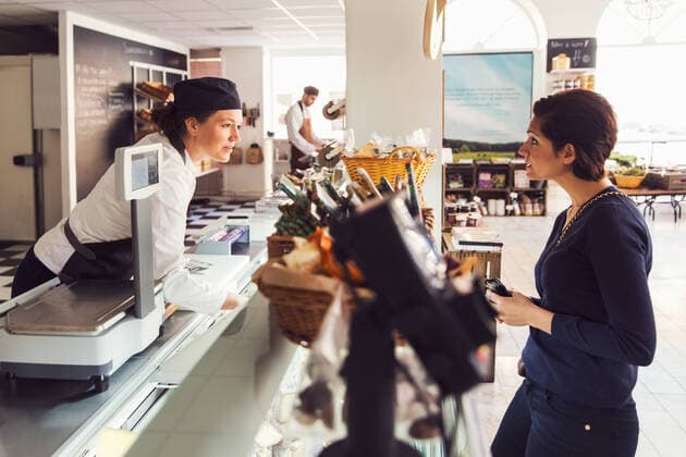 Side view of woman talking to saleswoman at counter at grocery store , model released, property released Copyright: xMaskotx , MA51874