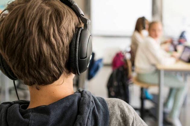 Rear view of boy listening to headphones in classroom , model released, property released Copyright: xMaskotx , MA51917