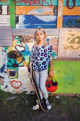 IMAGO Creative: NGO, Kunst im öffentlichen Raum und Kulturinitiativen Portrait of girl holding skateboard and helmet while standing against graffiti wall , model released Copyright: xMaskotx , MA53729