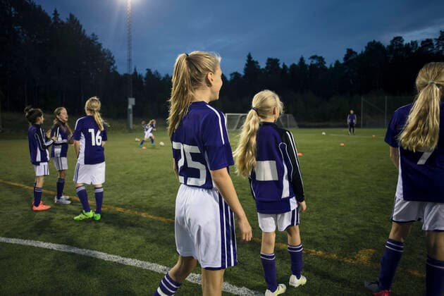 IMAGO Creative: Lokalhelden - Jugendsportbildung Rear view of athletes standing on soccer field against sky at dusk , model released Copyright: xMaskotx , MA55665