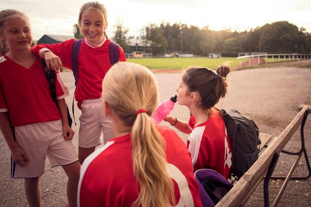 Happy friends talking on footpath against soccer field , model released Copyright: xMaskotx , MA55733