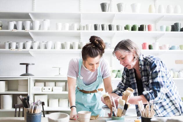 IMAGO Kreativ: Bildung, Kunsterziehung Young female potter looking at mature artist molding clay at workshop , model released, property released Copyright: xMaskotx , MA55843
