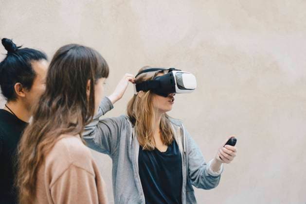 Computer programmer using remote control while wearing VR glasses by colleagues in office , model released, property released Copyright: xMaskotx , MA56967