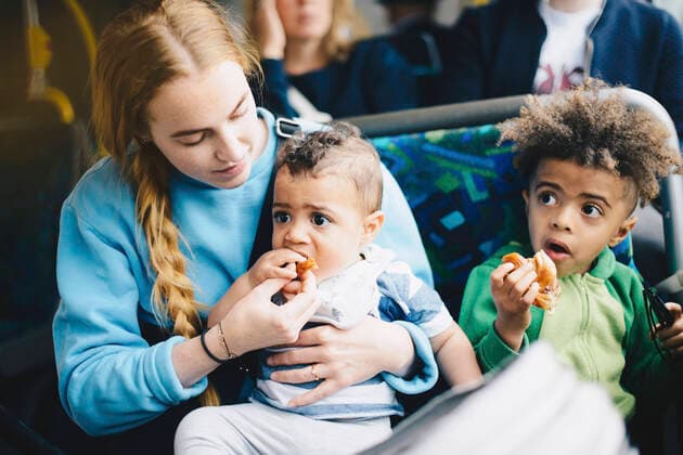 IMAGO Creative: Gesellschaft, Mobilität auf dem Land IMAGO Creative: Stadt-Dichotomien Mother feeding baby boy while sitting with son in bus , model released Copyright: xMaskotx , MA57526