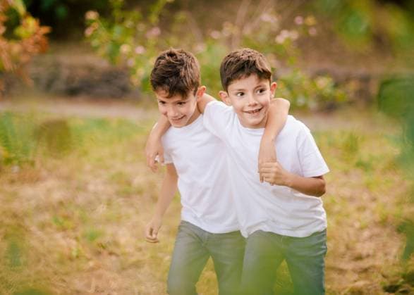 IMAGO Kreativ: Bruderschaft Happy twin boys hugging and looking away in park, Model released Copyright: xGabrielxTrujillox MR