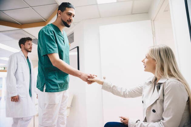 IMAGO Creative: Brustkrebsmonat Side view of female patient shaking hands with young male nurse in hospital , model released, property released Copyright: xMaskotx , MA58185