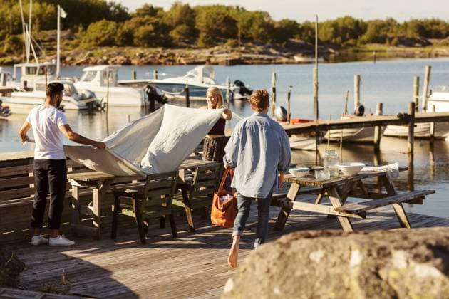 Friends putting cloth on table at jetty on sunny day , model released Copyright: xMaskotx , MA58599