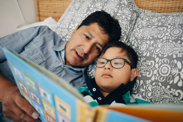 Father reading book to son while lying on bed at home , model released, property released Copyright: xMaskotx , MA59937