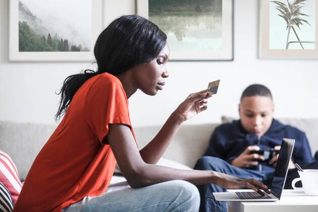 Mother holding credit card while using laptop with son in background at home , model released, property released Copyright: xMaskotx , MA60938