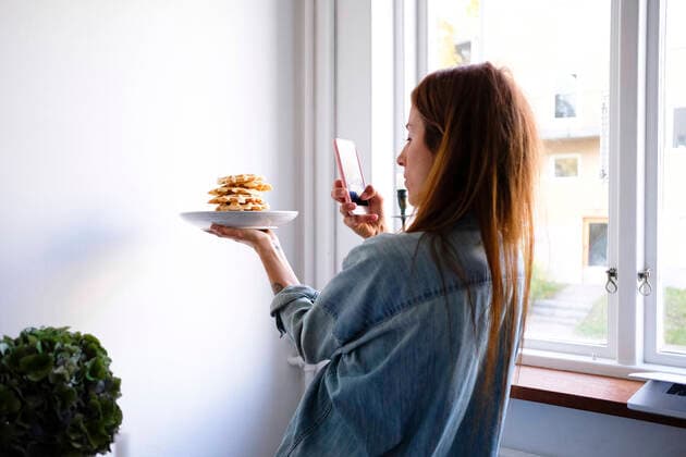 Woman photographing waffles through smart phone in plate by wall at home , model released, property released Copyright: xMaskotx , MA61934