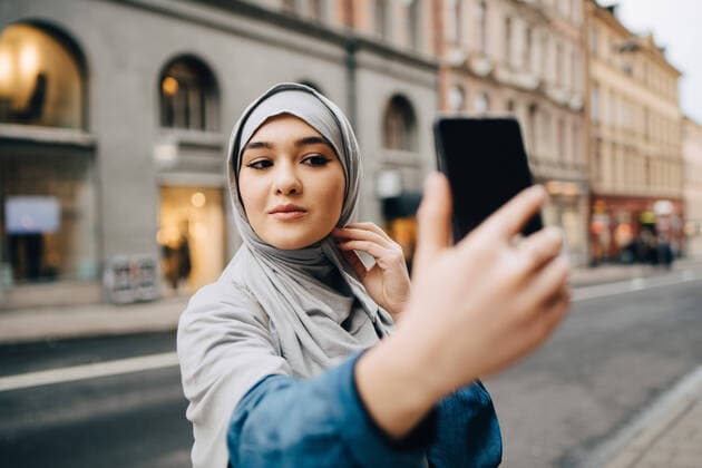 Confident young Muslim woman taking selfie on city street , model released Copyright: xMaskotx , MA62100
