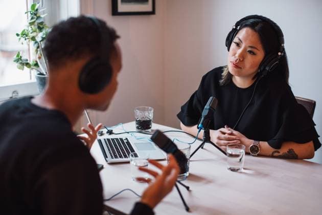 Bloggers talking through microphones and headphones sitting at table , model released, property released Copyright: xMaskotx , MA62124