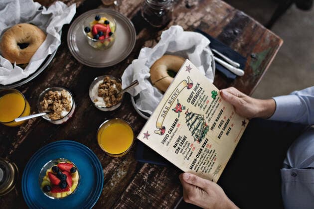 IMAGO Creative: Landleben - Essen Midsection of man holding menu while having brunch at dining table , model released, property released Copyright: xMaskotx , MA62448
