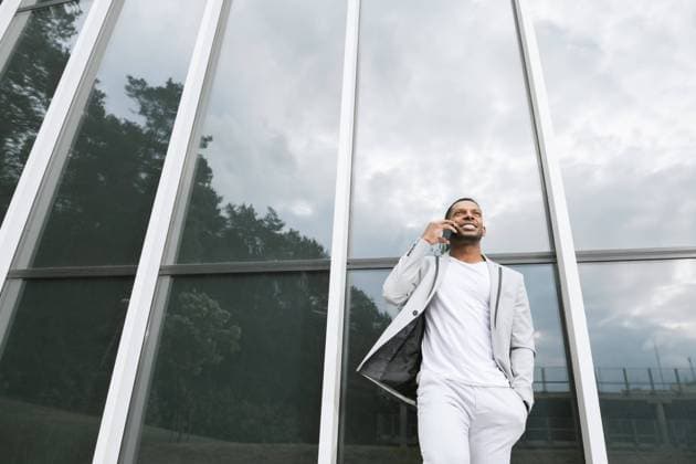 Elegant black man talking smartphone leaning building Copyright: xHernandezxAndxSorokinax Model Released