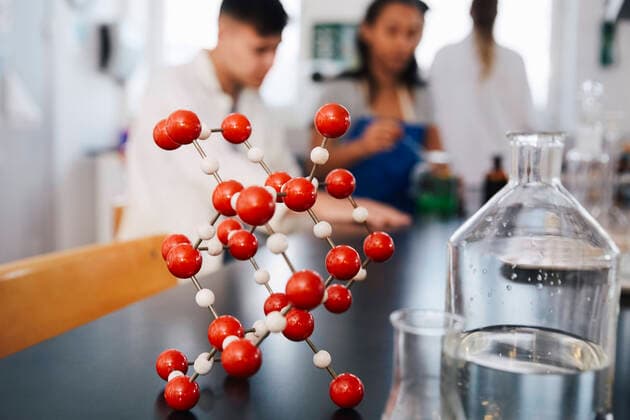 Molecular structure by glassware on table against young students in chemistry laboratory , model released, property released Copyright: xMaskotx , MA62588