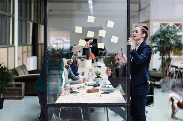 Businesswomen explaining adhesive notes to colleagues in meeting at office , model released, property released Copyright: xMaskotx , MA62974