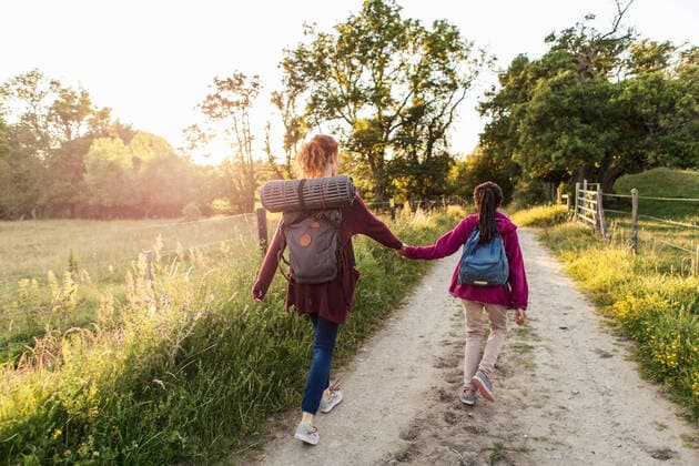 Rear view of mother and daughter holding hands while hiking on dirt road in forest , model released Copyright: xKentarooxTrymanx , MA63479