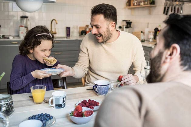 Laughing father holding plate while daughter eating pancake at table , model released, property released Copyright: xMaskotx , MA64214