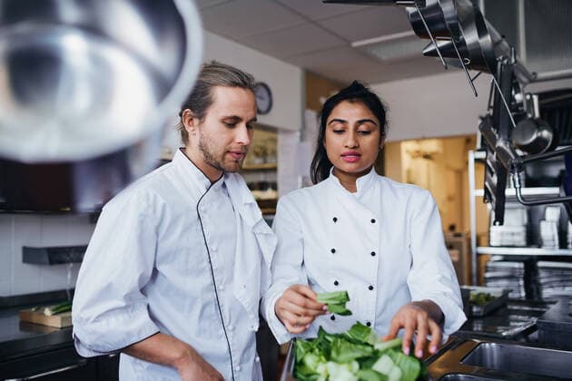 Female chef discussing with colleague over vegetable at commercial kitchen , model released, property released Copyright: xMaskotx , MA64597