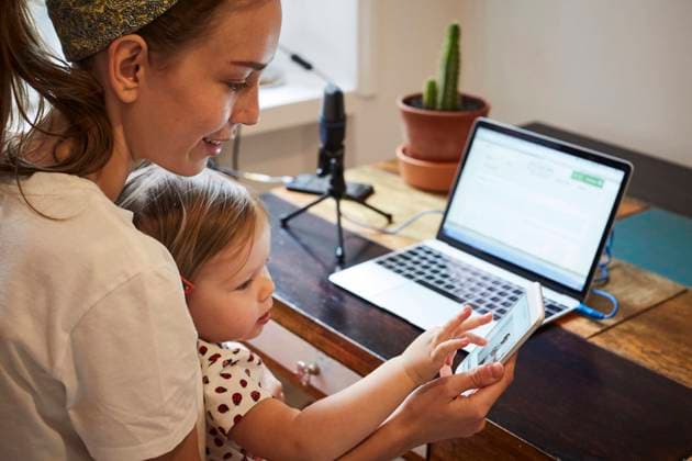 Podcaster showing mobile phone to daughter while using laptop at home , model released, property released Copyright: xMaskotx , MA64763