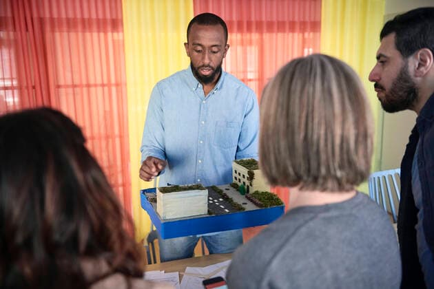 IMAGO Creative: Internationaler Tag der Architektur am 3. Oktober. Thema: Architektur zum Wohlfühlen Male engineer explaining colleagues over architectural model during meeting in office , model released, property released Copyright: xMaskotx , MA65063