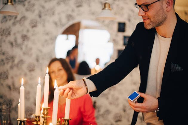 IMAGO Creative: Guten Rutsch IMAGO Creative: Landleben - Essen Smiling man igniting candles at dinner party with friend in background , model released, property released Copyright: xMaskotx , MA65110