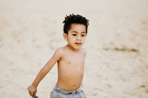 funny African American boy with stick playing on sandy shore near sea Copyright: xIsabelxAlcainex Model Released