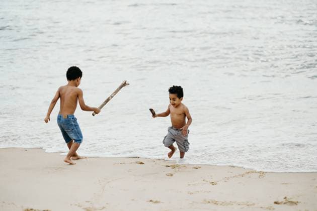 IMAGO Kreativ: Bruderschaft Two funny African American brothers with sticks playing together on sandy shore near sea Copyright: xIsabelxAlcainex Model Released