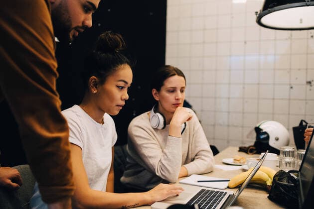 Confident young multi-ethnic colleagues discussing over laptop at office , model released, property released Copyright: xMaskotx , MA66037