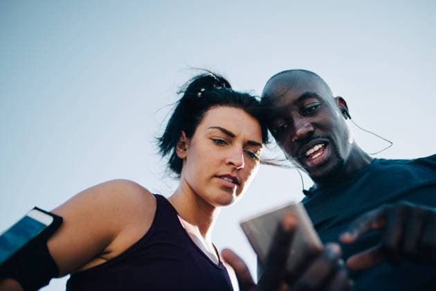 IMAGO Creative: Sport Start-Up Low angle view of sportsman showing mobile phone to female athlete while standing outdoors , model released Copyright: xMaskotx , MA67333