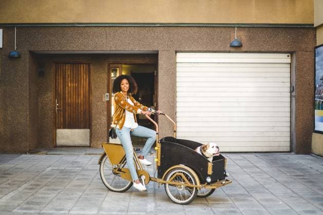 IMAGO Creative, Urban Lifestyle Full length of mid adult woman riding bicycle cart with dog against building , model released Copyright: xMaskotx , MA67437