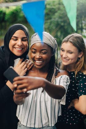 IMAGO Creative: Kollidierende Kulturen Happy multi-ethnic female friends taking selfie through smart phone in backyard , model released, property released Copyright: xMaskotx , MA68063