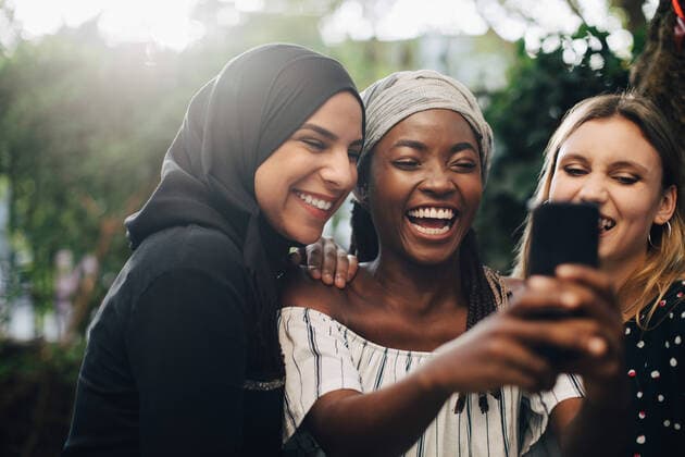 Smiling multi-ethnic female friends taking selfie through mobile phone in backyard , model released, property released Copyright: xMaskotx , MA68065