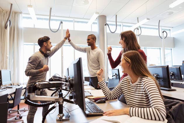 Happy male and female students celebrating success while using computers at library in university , model released, property released Copyright: xKentarooxTrymanx , MA68336