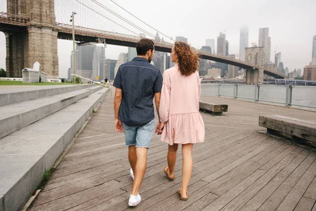IMAGO Creative: Welttourismustag am 27. September Back view of happy couple in casual wear on wooden promenade during city stroll near river while on vacations, Model released Copyright: xJakexJakabx MR