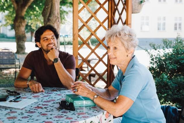 IMAGO Creative: Zivildienst und ehrenamtliches Engagement Smiling male caretaker looking at senior woman sitting with gift at back yard , model released, property released Copyright: xMaskotx , MA68880